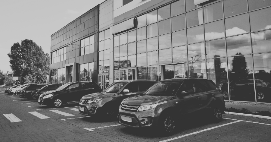 Cars lined up in front of glass windows at car dealership