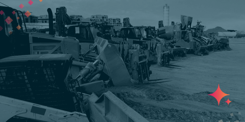 Row of heavy construction equipment including bulldozers, loaders, and excavators lined up on a dirt job site.