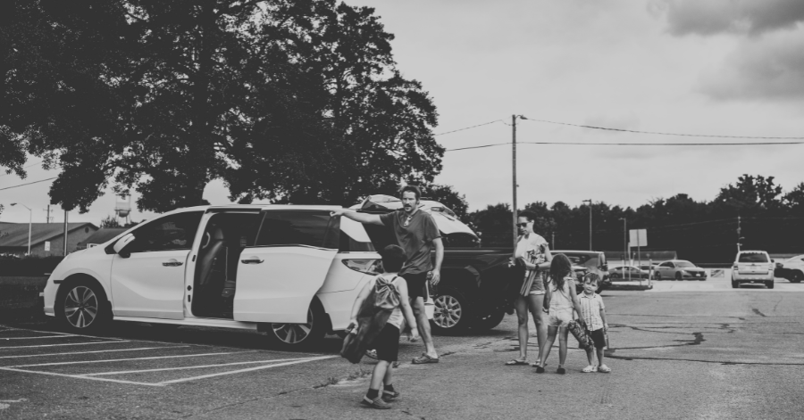 Young brother and sister help their mom unload the van in a parking lot when arriving at a park to go fishing with their uncle and cousin, during a summer visit in North Carolina.