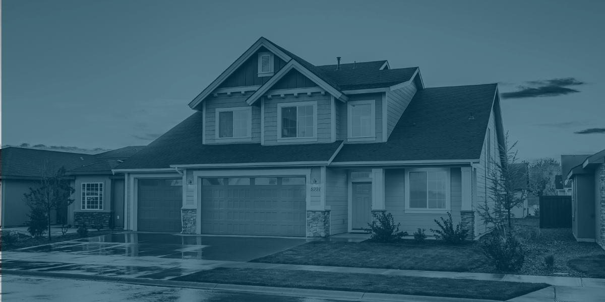 Front view of a modern suburban home with a three-car garage, landscaped yard, and wet driveway at dusk.