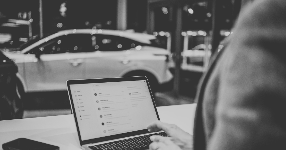 An image of an automtive dealership employee working on SEO strategy on her laptop in the dealership. 